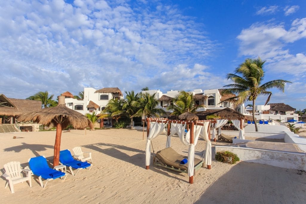 Palapa Papa Jack beach with thatched palapas, a curtained cabana and loungers — Playa del Carmen, Mexico
