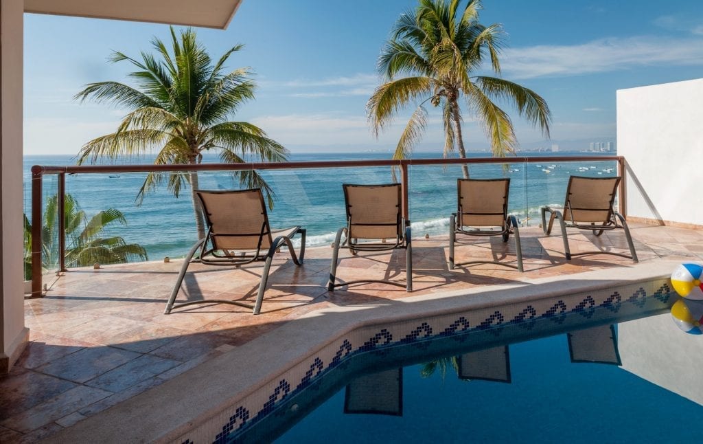 Vallarta Shores Sky Suite B daytime pool terrace, loungers along the glass rail — Puerto Vallarta, Mexico