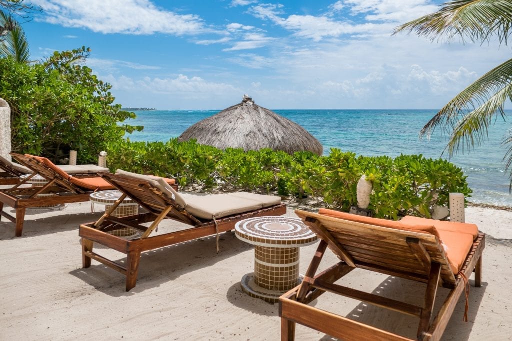 Villa Akumal Sunrise orange-cushioned loungers around the tiled drum table — Akumal, Mexico