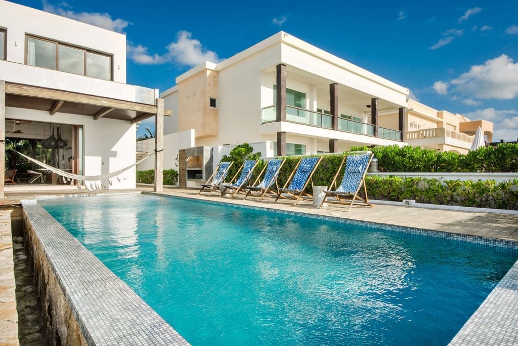 Villa Amara exterior with long pool and sun loungers beside the villa — Tulum, Mexico