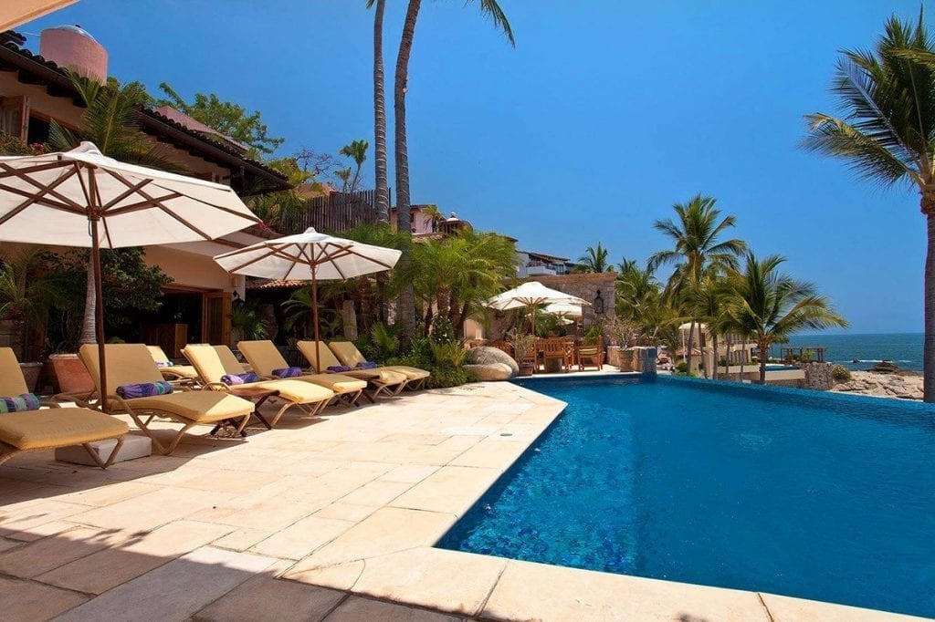 Villa Amapas South pool deck lined with a row of cushioned loungers and parasols — Puerto Vallarta, Mexico