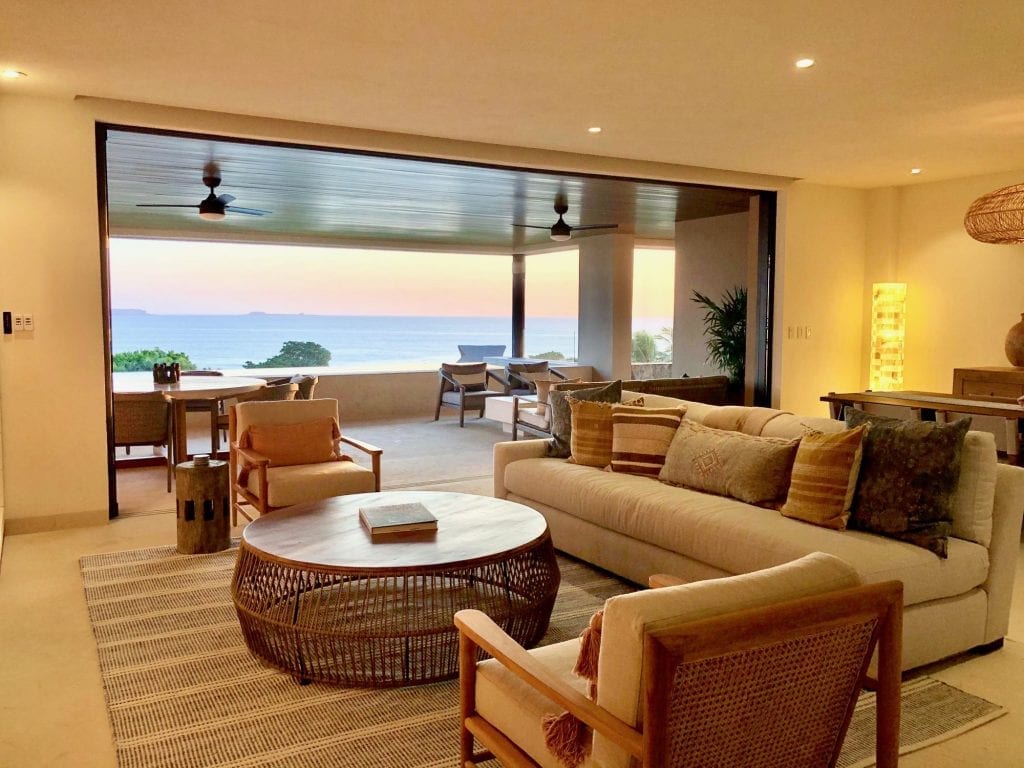 Condo Cualli living room with a white sofa and round woven table facing the sea — Punta Mita Nayarit, Mexico