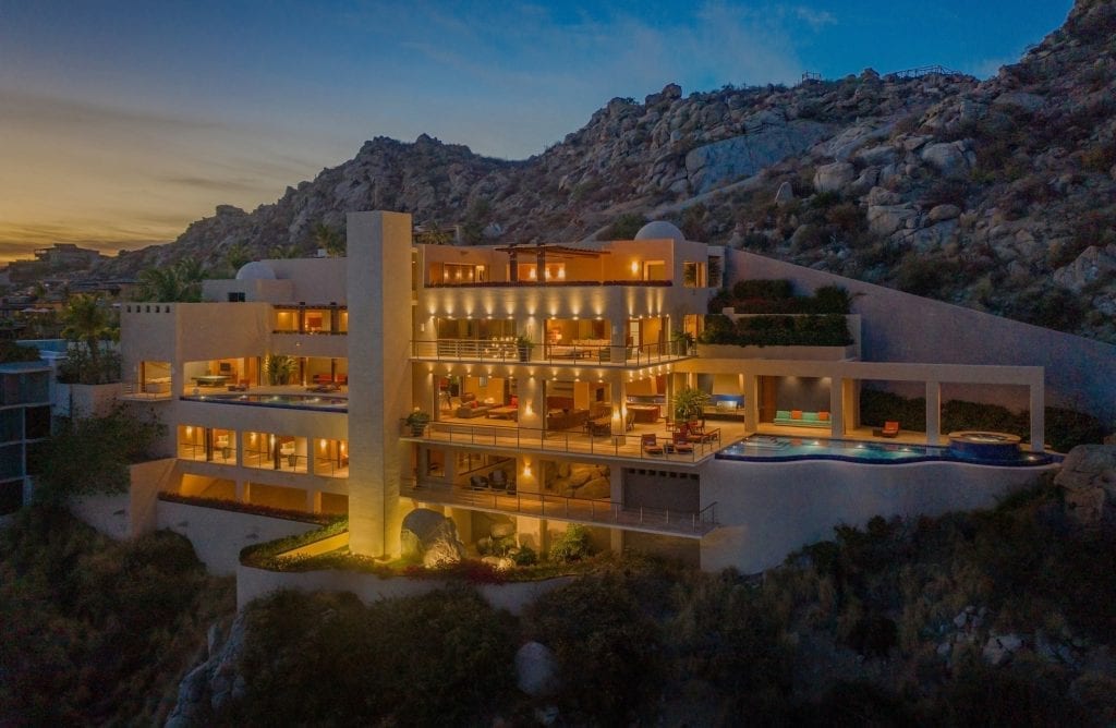 Villa Bellissima illuminated exterior on a rocky hillside at twilight — Los Cabos, Mexico