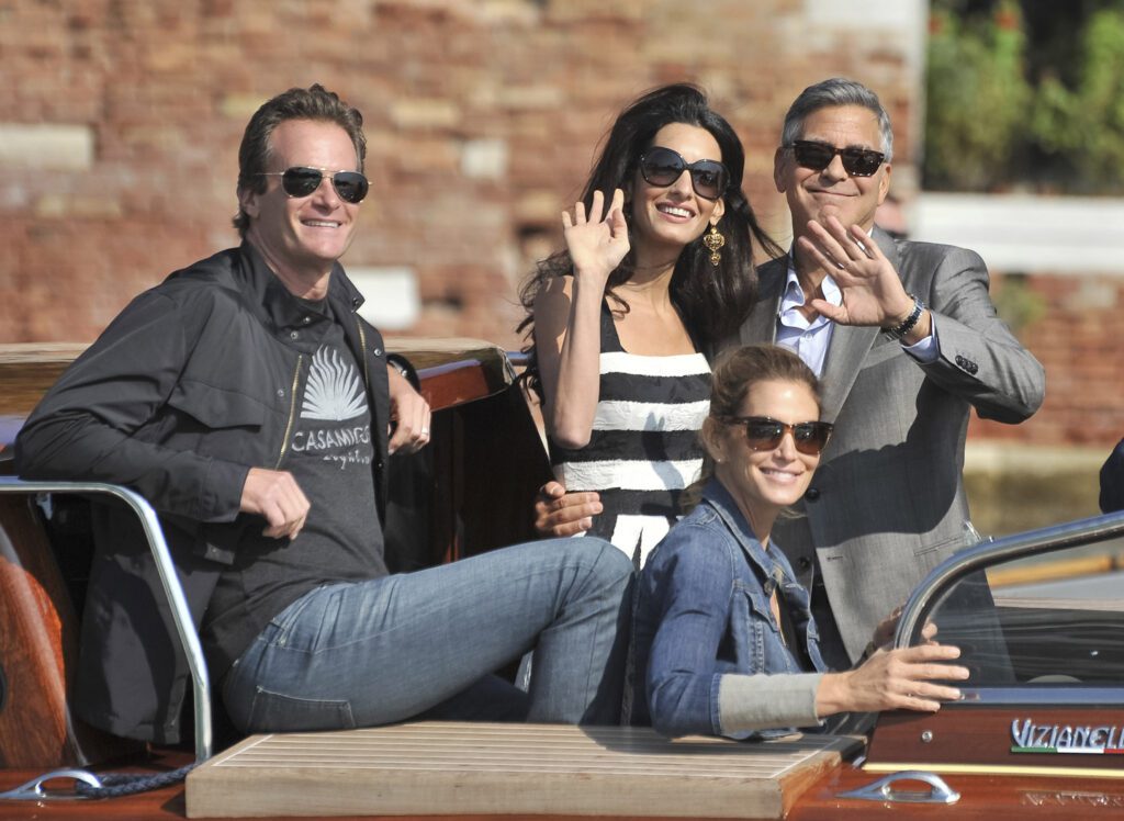 Four people pose joyfully on a stylish wooden boat near a luxury vacation villa rental in Mexico.