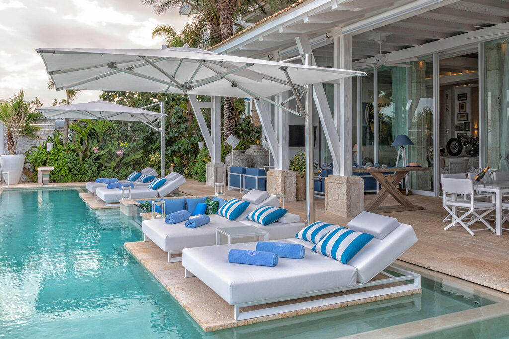 Villa Sha in Cancun: loungers on the pool's submerged shelf below a white cantilever umbrella