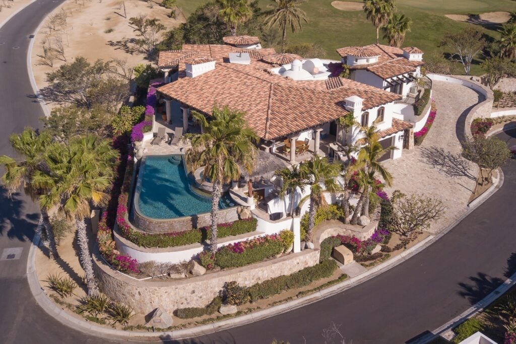 Casa Corona aerial view of the tiled-roof villa, pool, and curved road — Los Cabos, Mexico