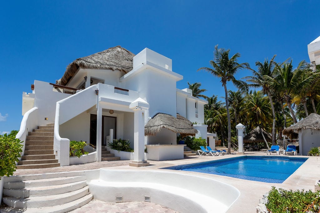 Casa del Secreto white villa with a poolside exterior staircase and loungers — Playa del Carmen, Mexico