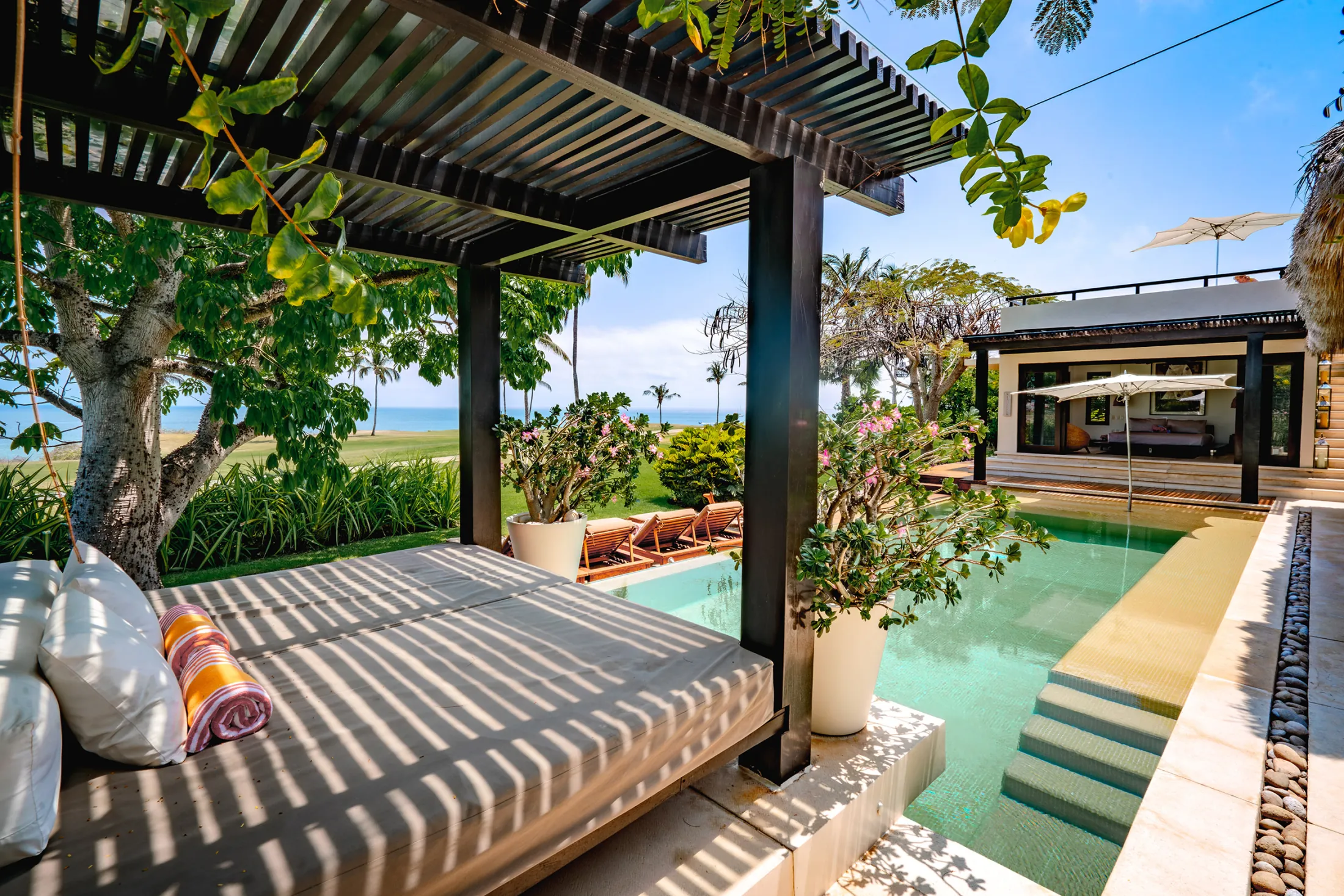 Casa Kalika cabana daybed beneath a slatted pergola beside the pool — Punta Mita Nayarit, Mexico