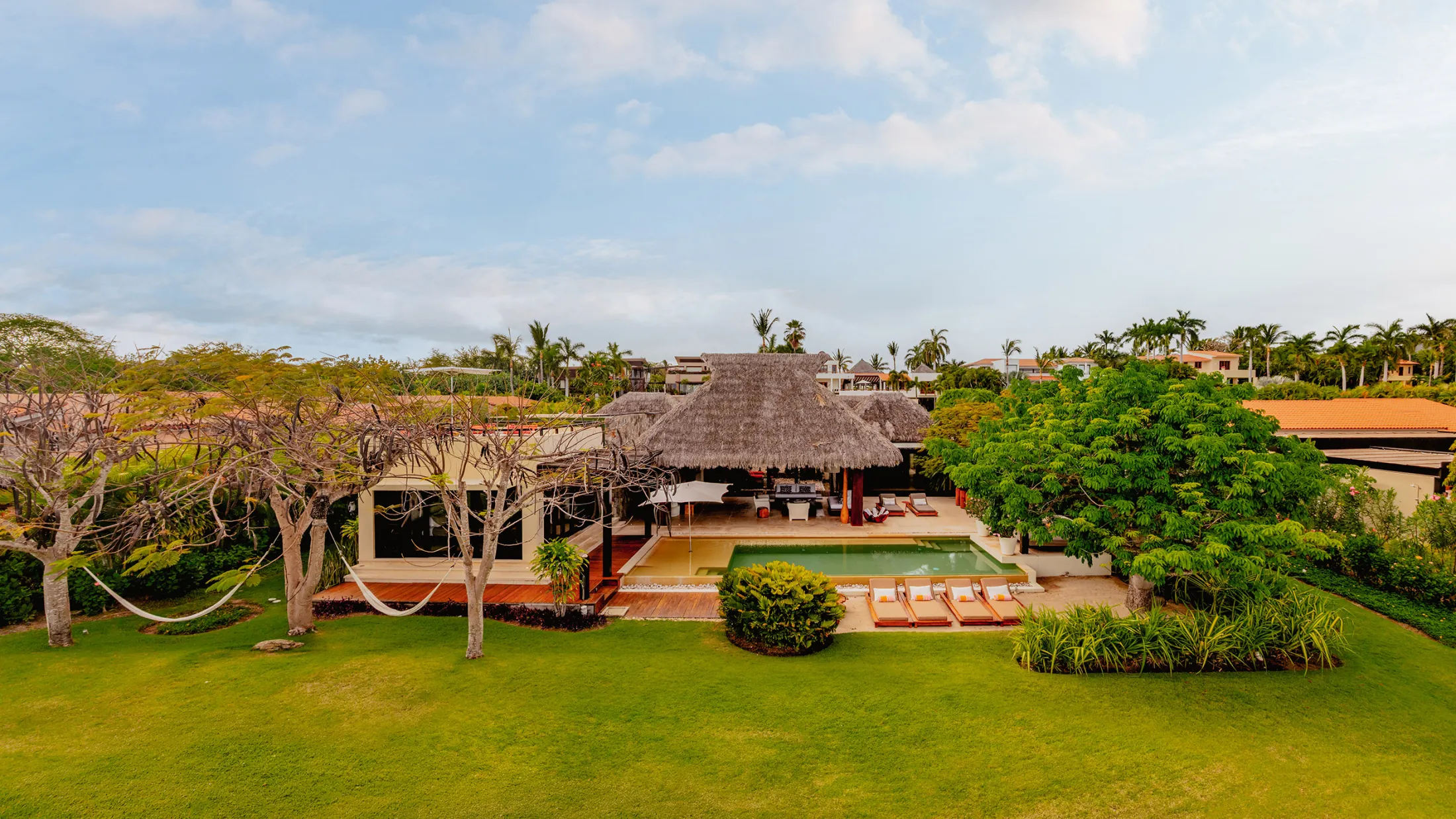 Casa Kalika thatched facade, hammocks and loungers across the lawn — Punta Mita Nayarit, Mexico