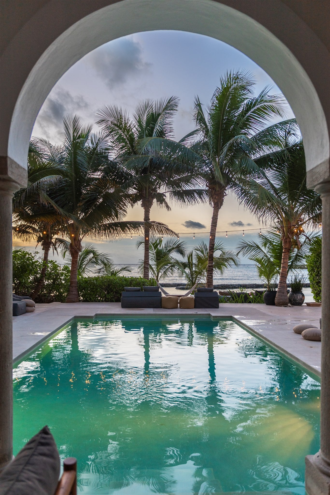 Hacienda Magica the pool and palms framed by a stone arch at dusk — Puerto Aventuras, Mexico