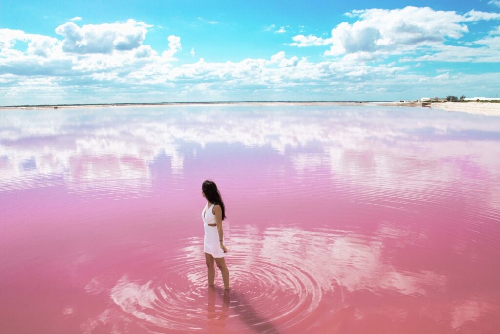 Woman standing in the shallow pink water of a broad lagoon