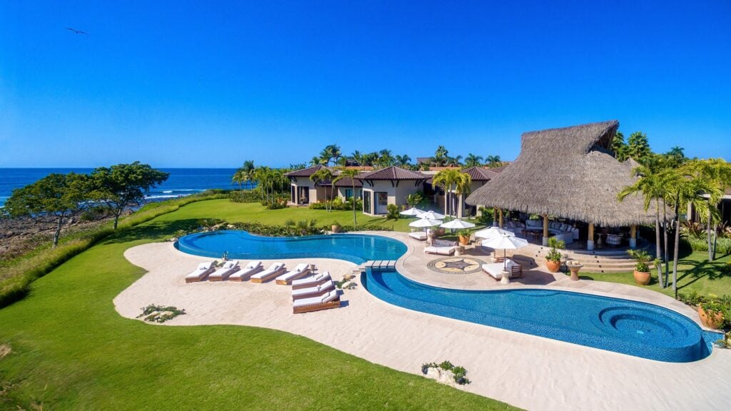Casa Wirikuta free-form pool with loungers and palapa above the ocean — Punta Mita, Mexico