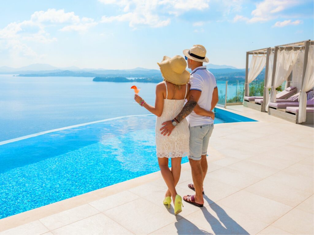 John and Sarah, happy customers standing by the pool of a Mexican villa, overlooking the ocean