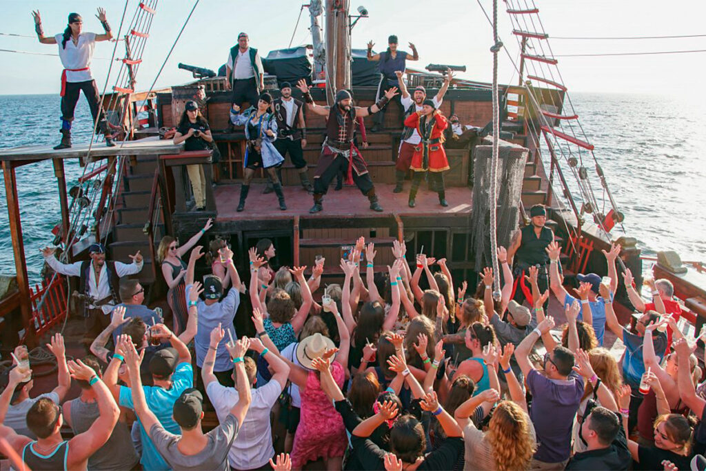 A lively pirate-themed party on a ship at sea, with costumed guests raising their hands. (Luxury villa: Mexico)