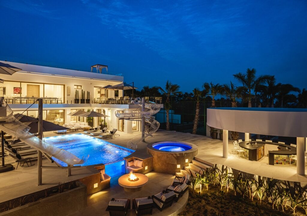 Casa Aqua Blanca illuminated pool and spa with fire pit at dusk — Los Cabos, Mexico