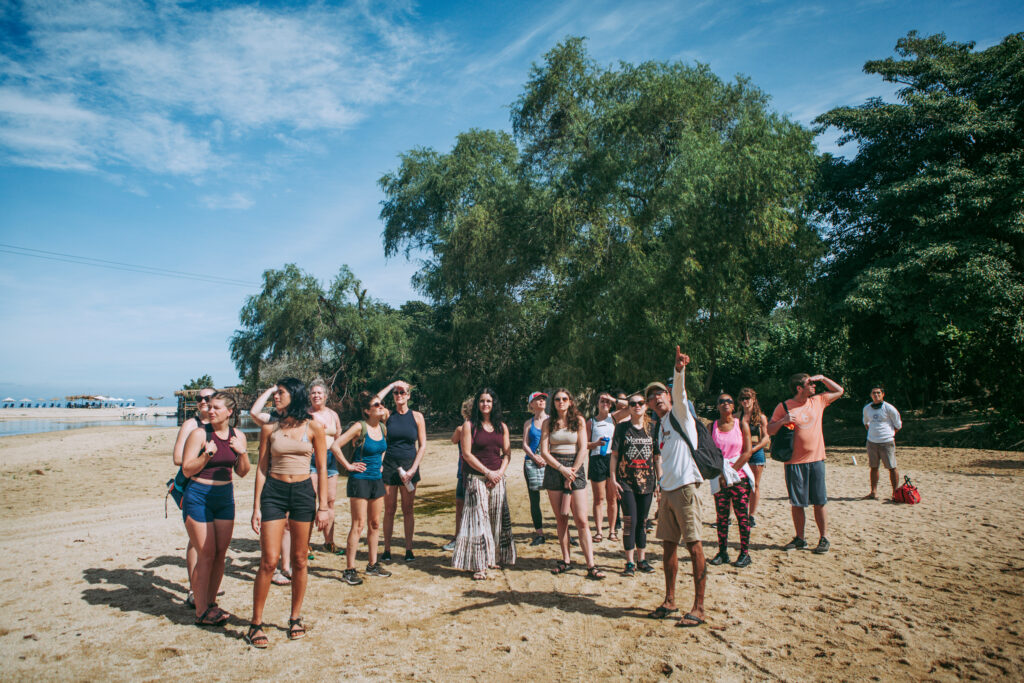 Group of excited tourists standing on the sandy Quimixto beach.