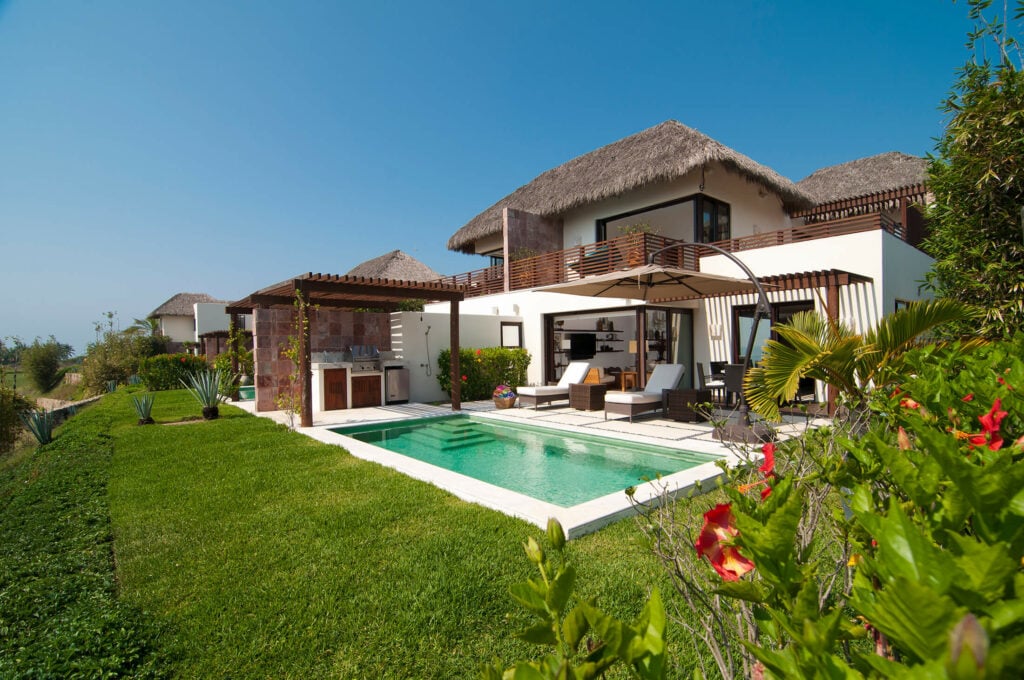 Villa Aquamarina garden view of the pool and villa facade from the lawn — Punta Mita Nayarit, Mexico
