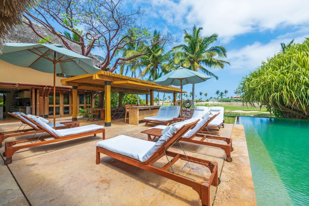 Villa Aire row of loungers along the pool with palapa bar behind — Punta Mita Nayarit, Mexico