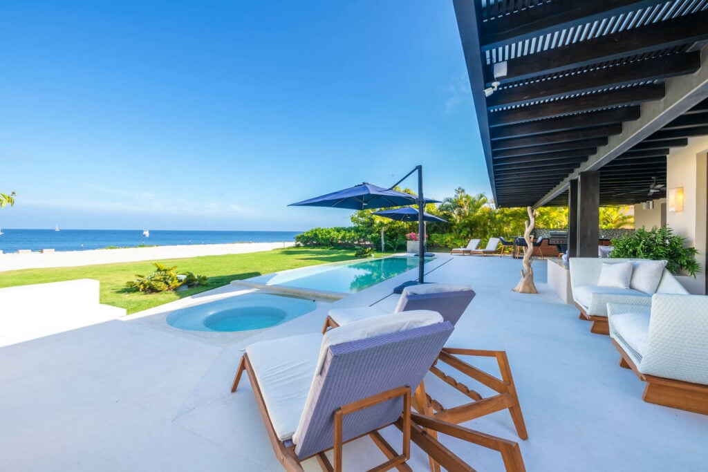 Villa Bahia Sunrise pool deck with white loungers and umbrella facing the ocean — Punta Mita Nayarit, Mexico