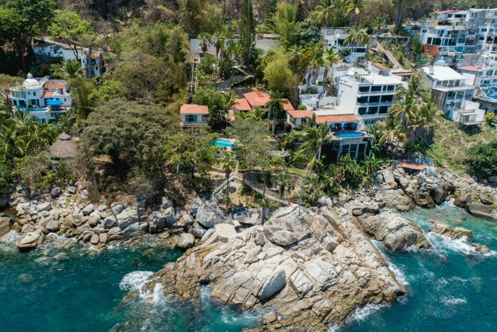 Villa Padre aerial view of hillside homes above a rocky turquoise cove — Puerto Vallarta, Mexico