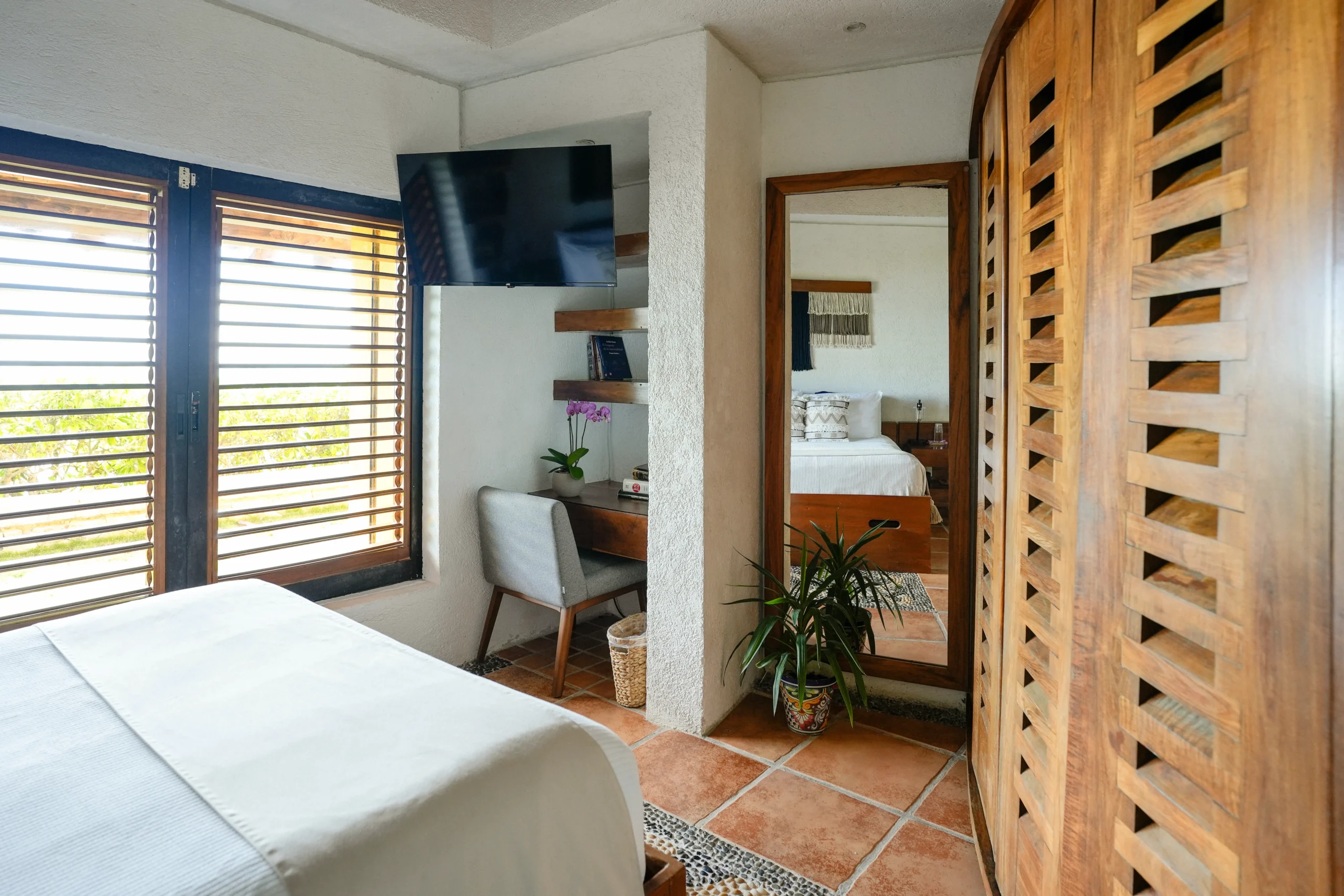 Casa Corazon bedroom with wooden louvered pivot screen and wall TV — Playa del Carmen, Mexico