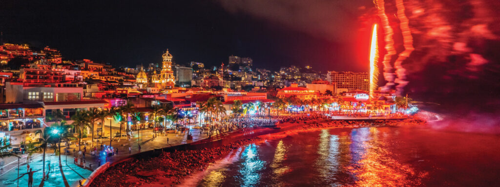 Spectacular fireworks display lighting up the night sky at the Malecon in Puerto Vallarta during the New Year's celebration, with crowds enjoying the festivity.