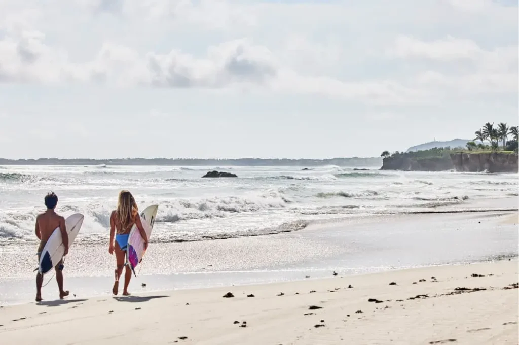 Two surfers preparing to ride the waves at the beach in front of Auberge Resort's Susurros de Corazón, Punta de Mita.