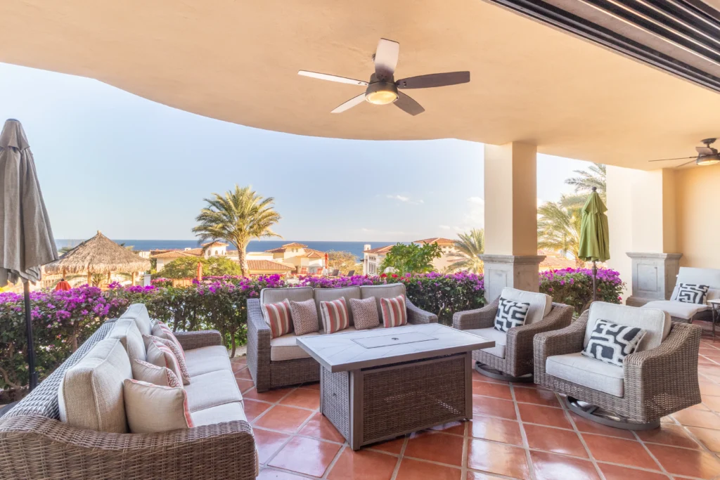Condo Puerta del Sol C104 covered terrace with wicker lounge seating and ocean view — Los Cabos, Mexico