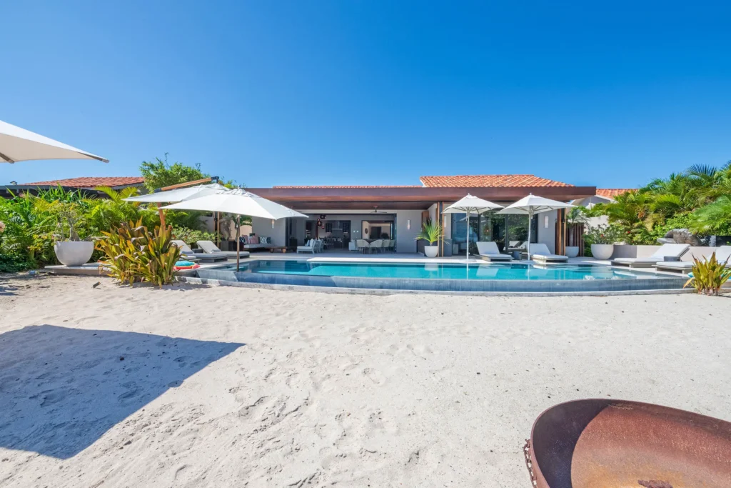Villa Tres Olas villa and pool seen across a sunlit sandy yard — Punta Mita Nayarit, Mexico