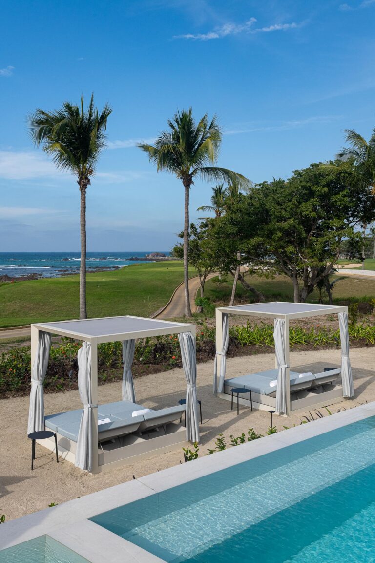 White cabanas by a turquoise pool at Punta Pacifico, Punta Mita, Mexico; ocean view framed by palms.