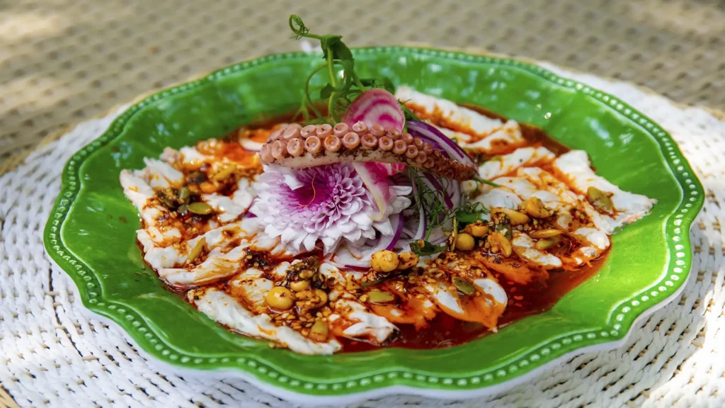 Seafood dish at Santuario Yelapa Mexico Wellness & Yoga Retreat with fish, octopus, red onions, and edible flowers.