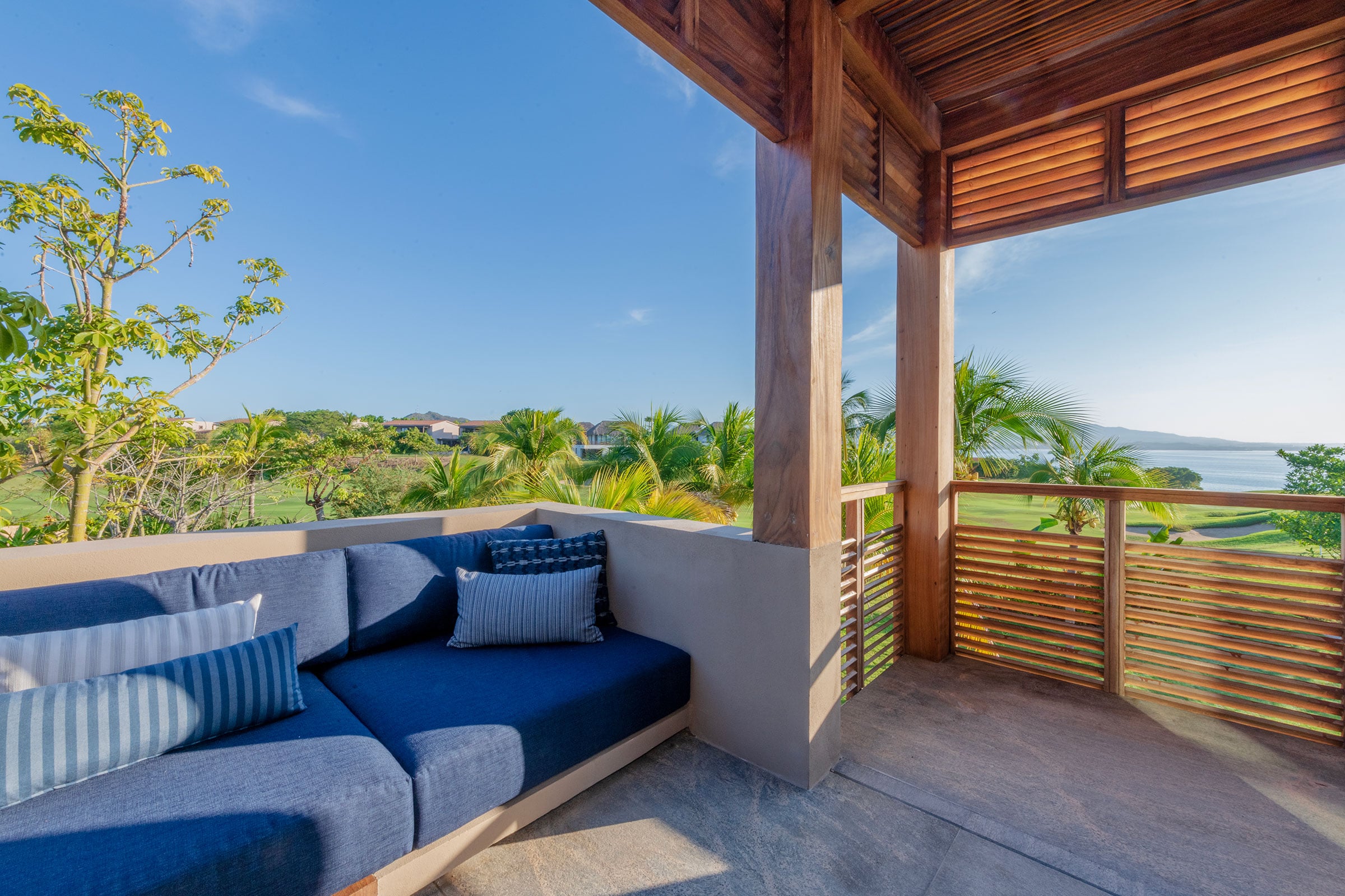 Casa Balena a blue corner sofa on the shaded terrace behind a slatted rail — Punta Mita, Mexico