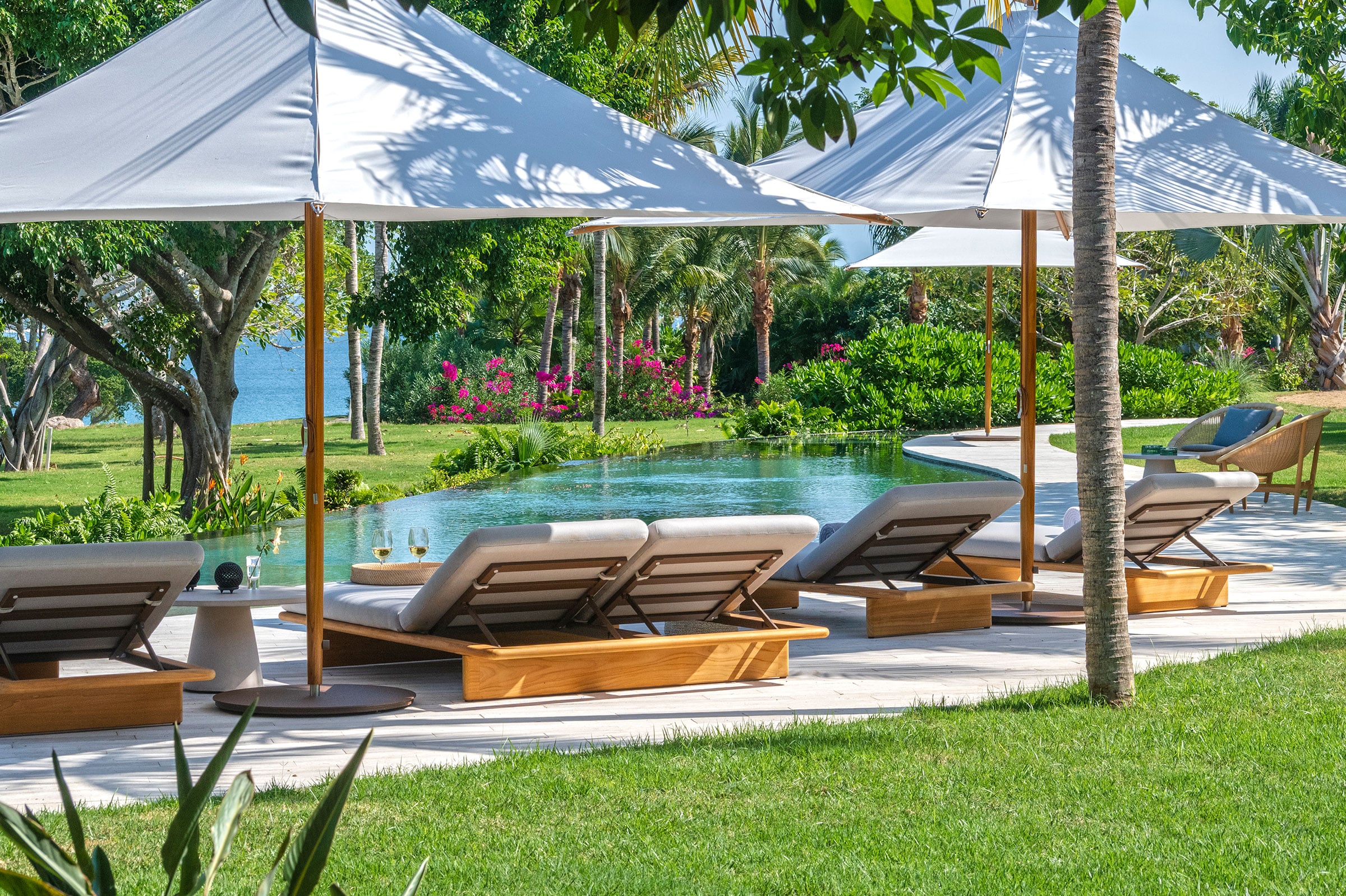 Casa Balena loungers and shade sails beside the curving pool on the lawn — Punta Mita, Mexico