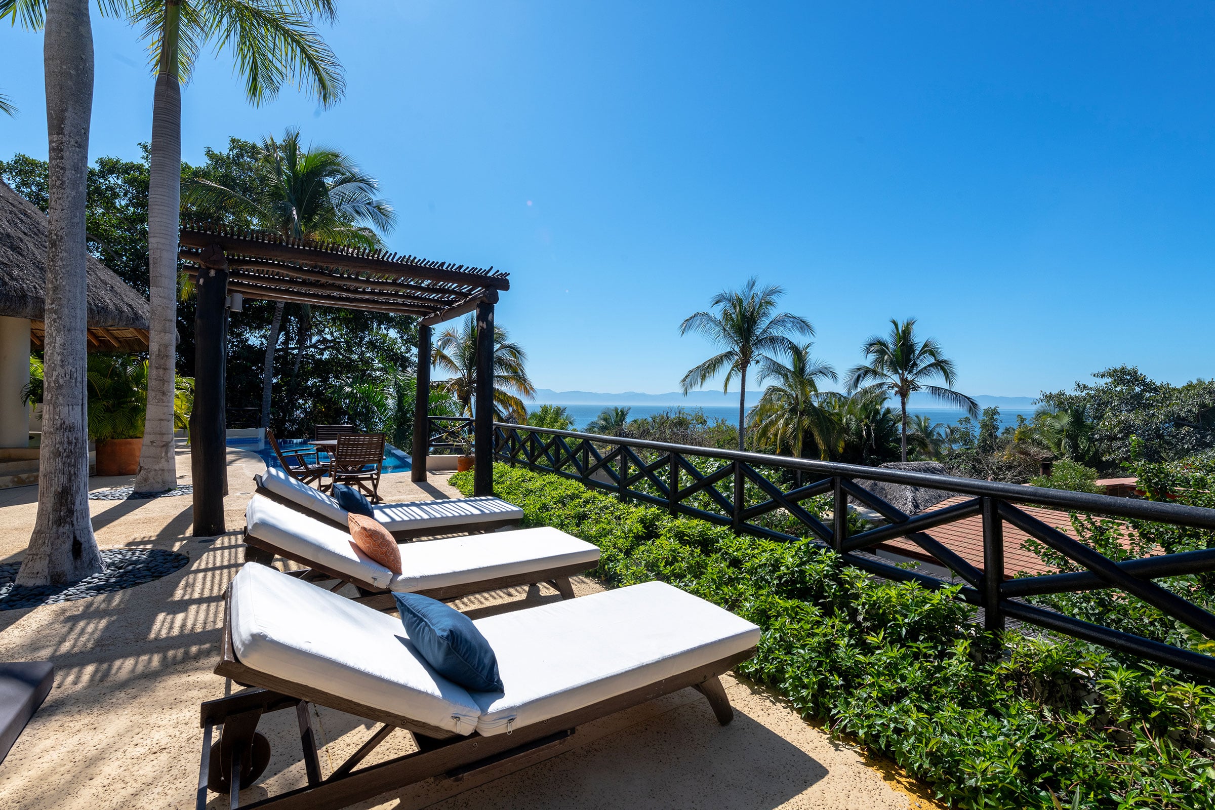 Casa Caracol two cushioned loungers on the gravel terrace behind a rail of hedging — Punta Mita, Mexico