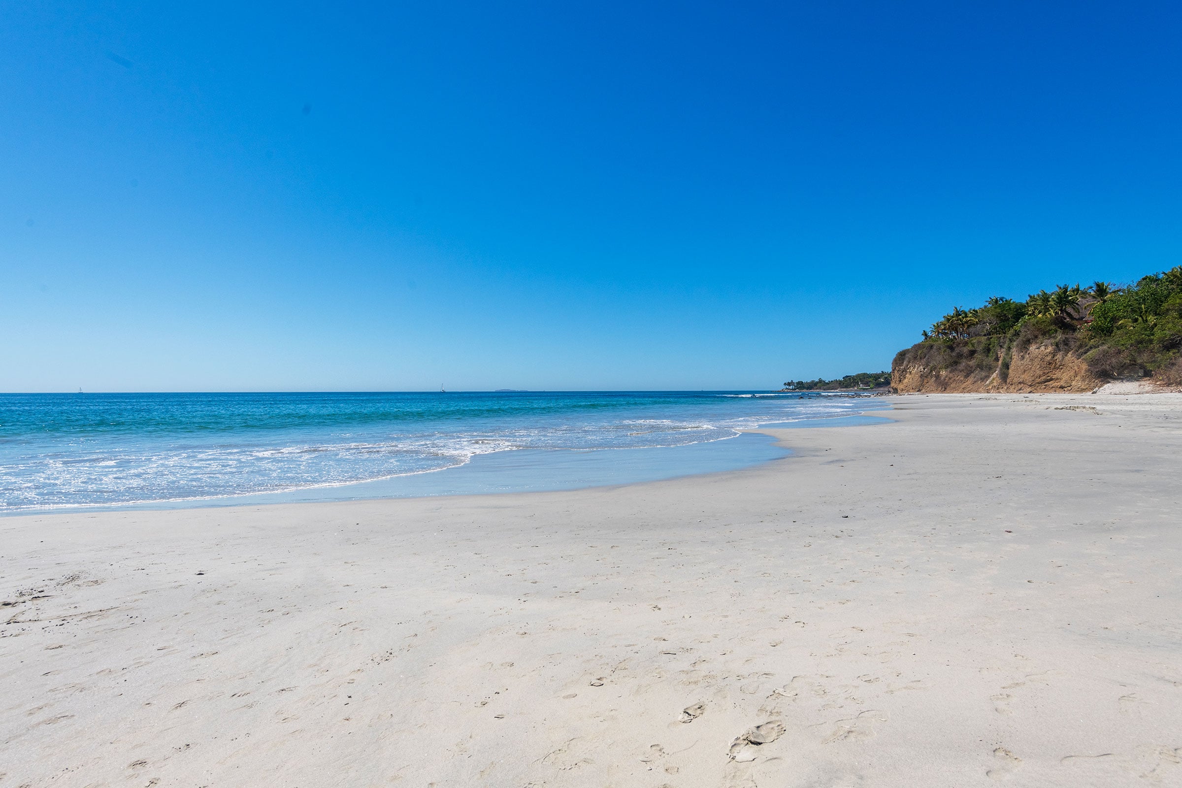 Casa Caracol an empty sand beach with surf running along it to a headland — Punta Mita, Mexico