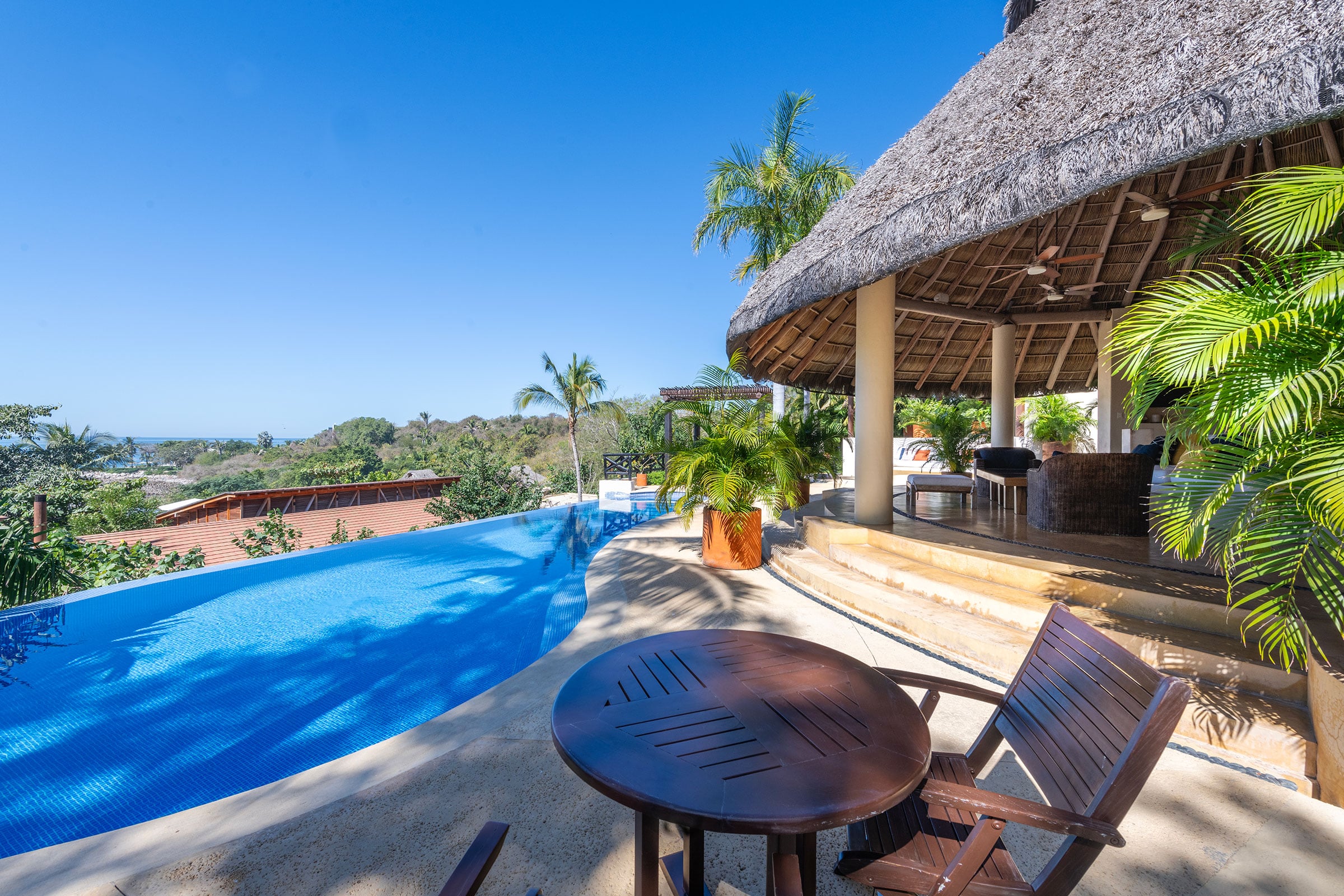Casa Caracol a round table and folding chairs beside the pool below the palapa — Punta Mita, Mexico