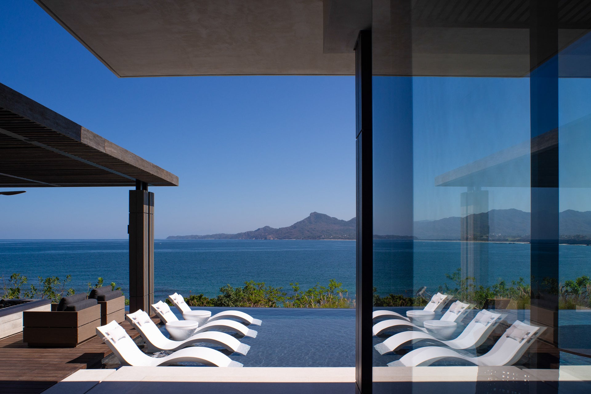 Casa Kupuri 32 white sculpted loungers on the deck above the bay and headland — Punta Mita, Mexico