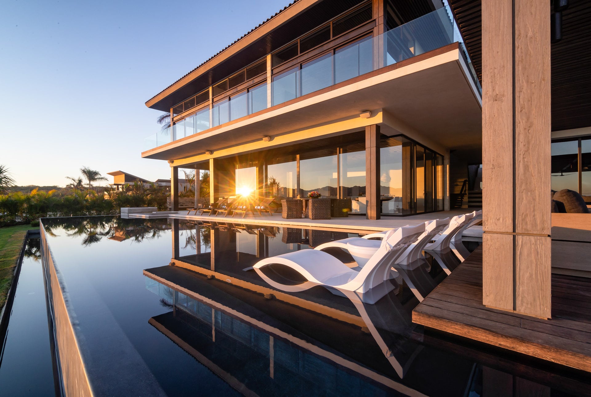 Casa Kupuri 32 sculpted loungers along the pool as the sun drops behind the house — Punta Mita, Mexico