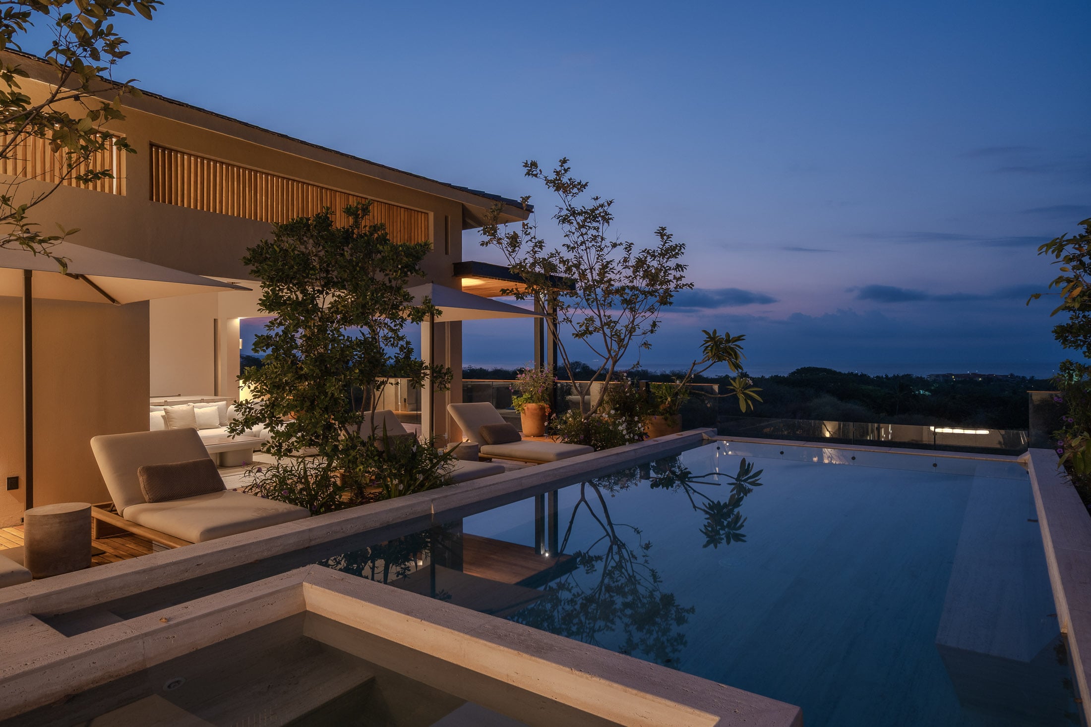Casa Tuki daybeds along the dark pool reflecting the house at nightfall — Punta Mita, Mexico