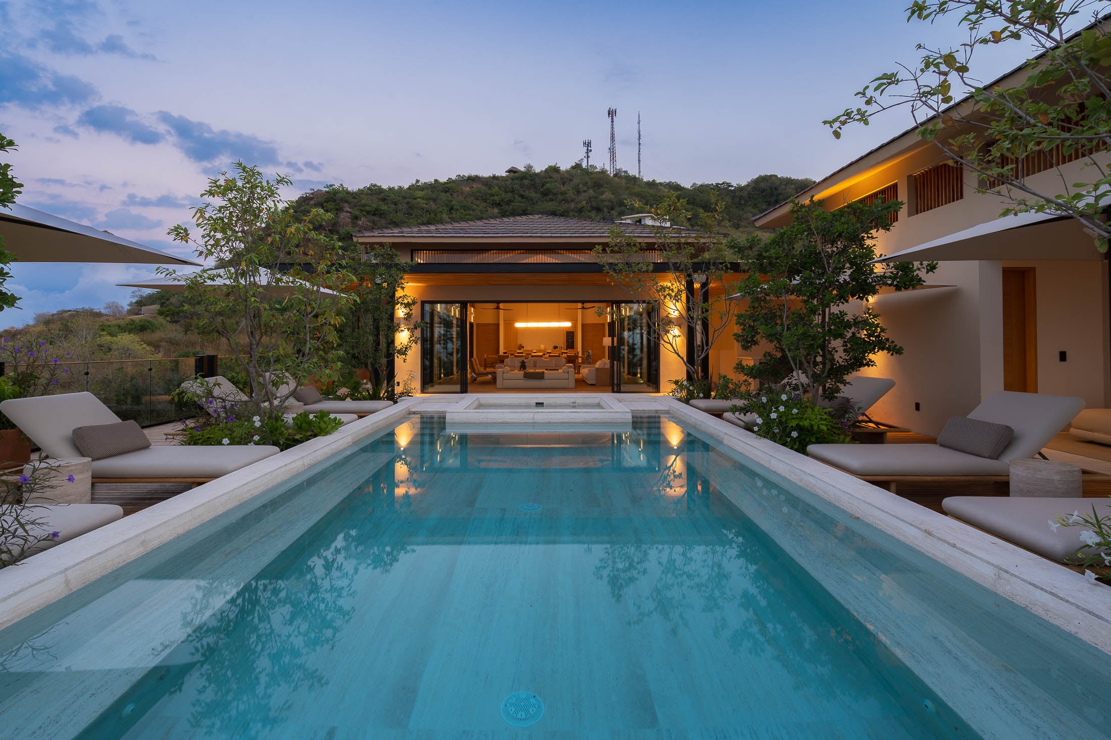 Casa Tuki the lit pool with daybeds either side and the house beyond at dusk — Punta Mita, Mexico