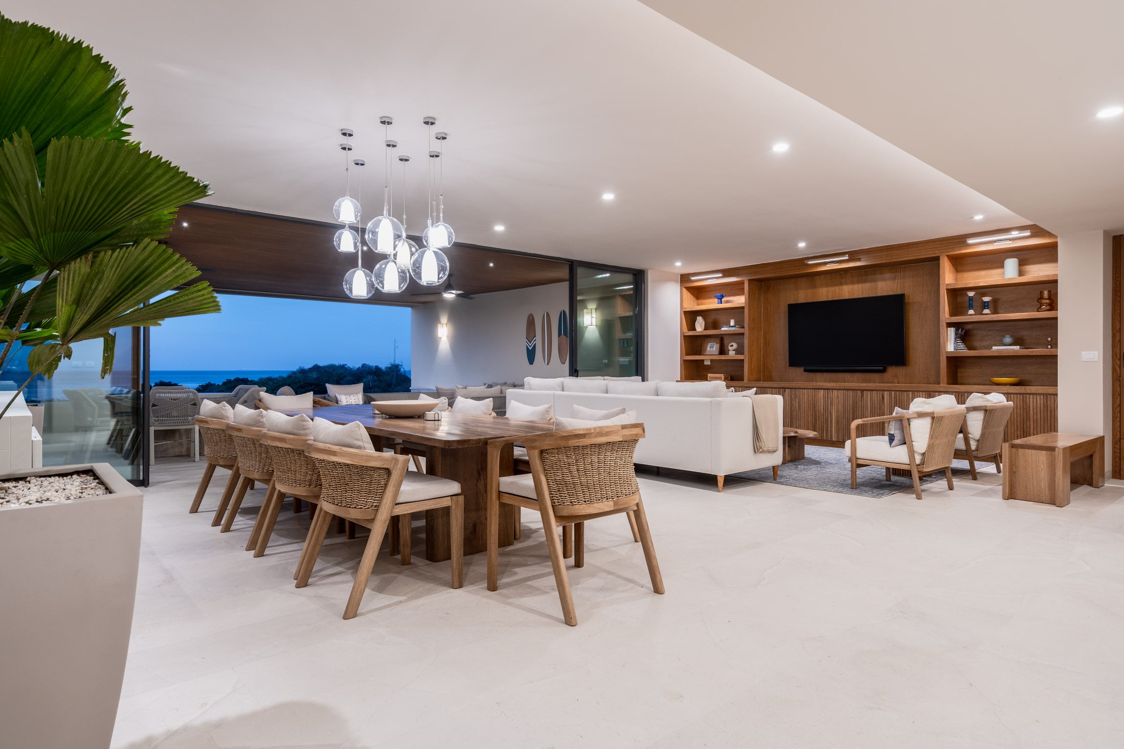 Condo Amor y Surf the dining table and living room open to the terrace at dusk — Punta Mita, Mexico