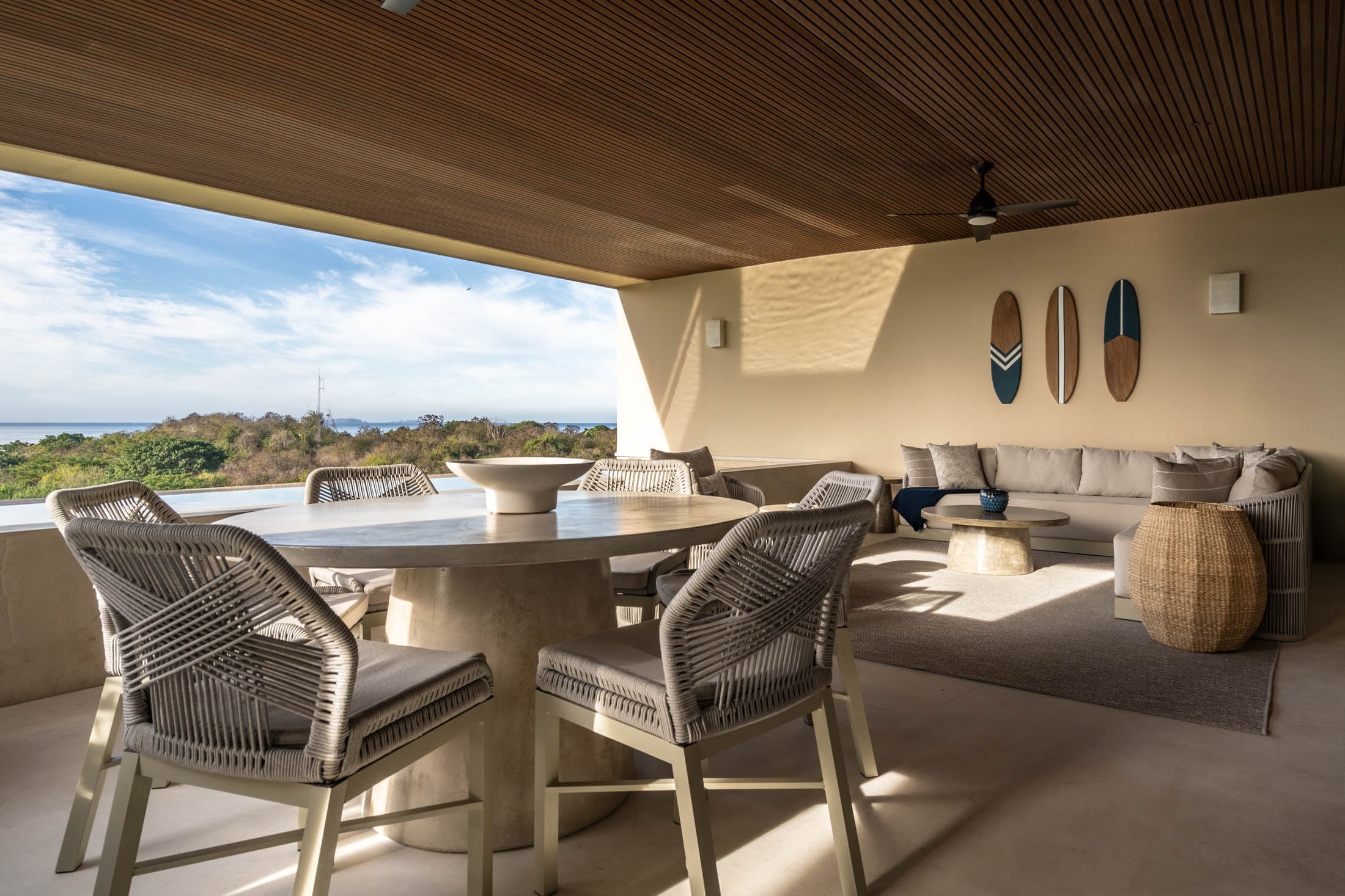Condo Amor y Surf a round table and woven chairs on the terrace under the slatted ceiling — Punta Mita, Mexico