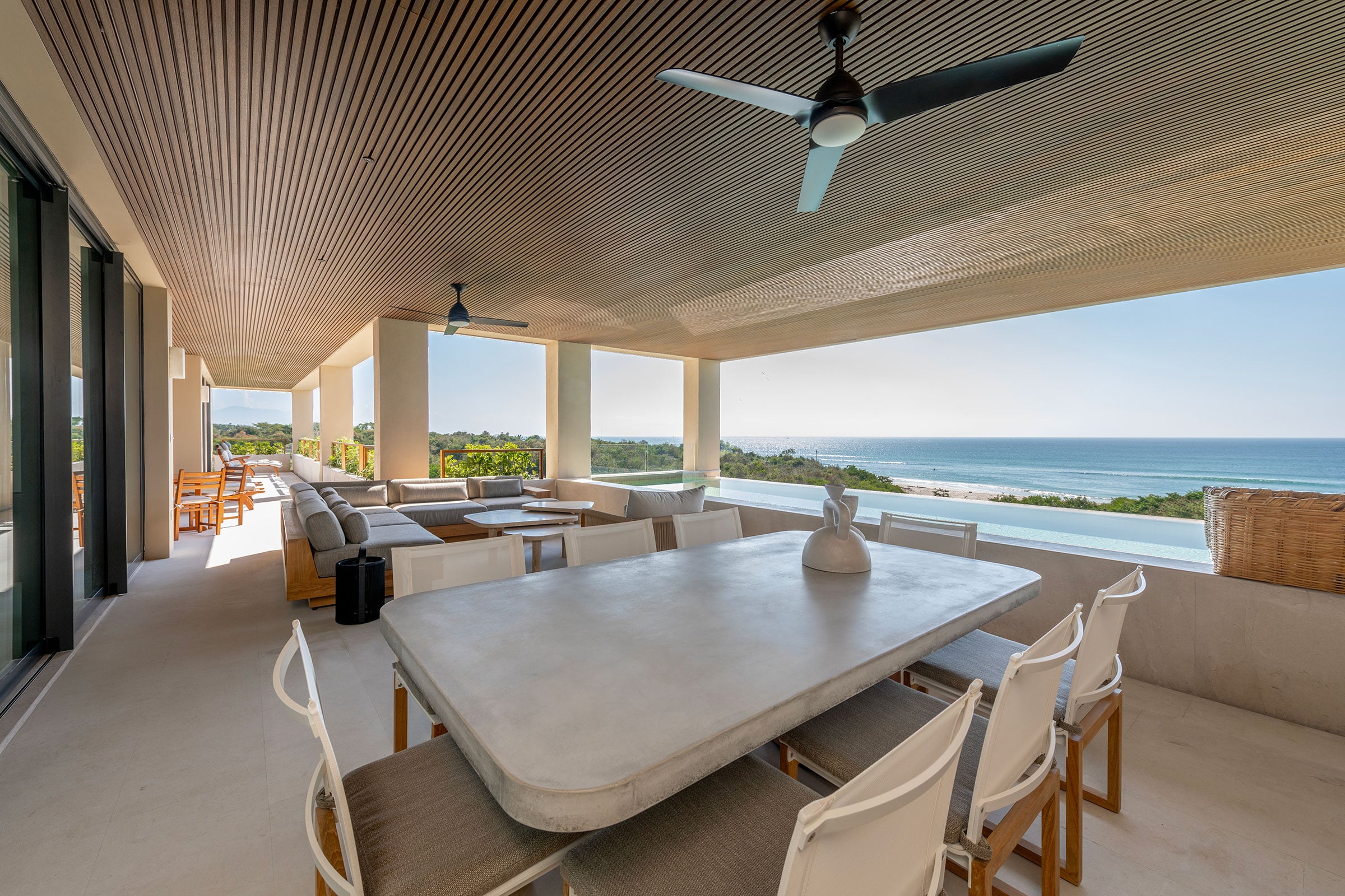 Condo Raya the long stone dining table and chairs on the terrace under ceiling fans — Punta Mita, Mexico