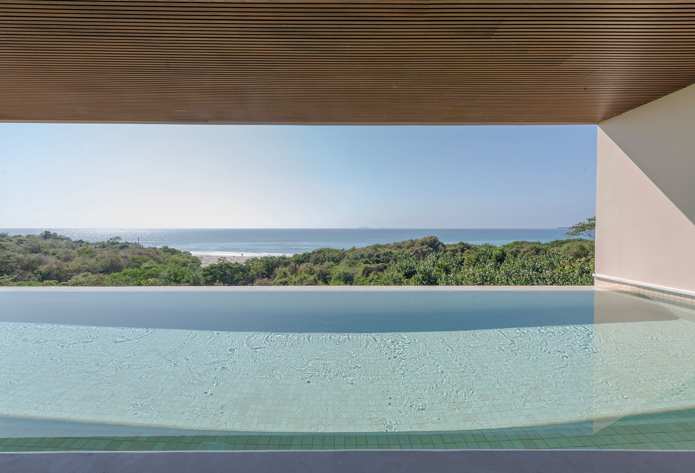 Condo Raya the infinity pool edge below the slatted timber soffit above the scrub — Punta Mita, Mexico