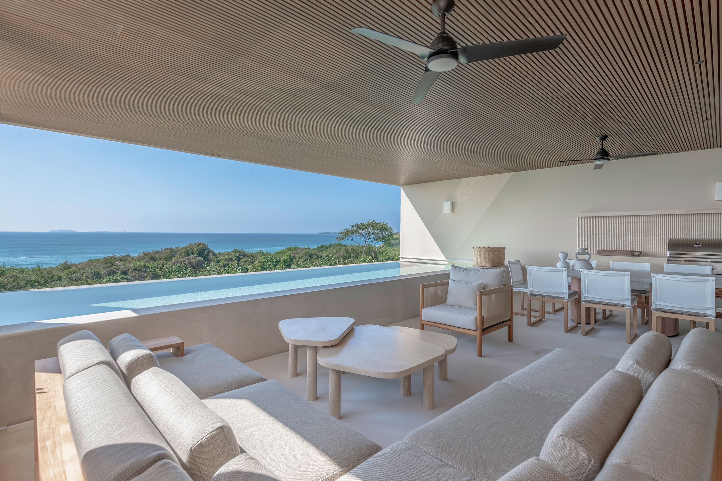 Condo Raya deep terrace sofas and round tables looking along the pool to the sea — Punta Mita, Mexico