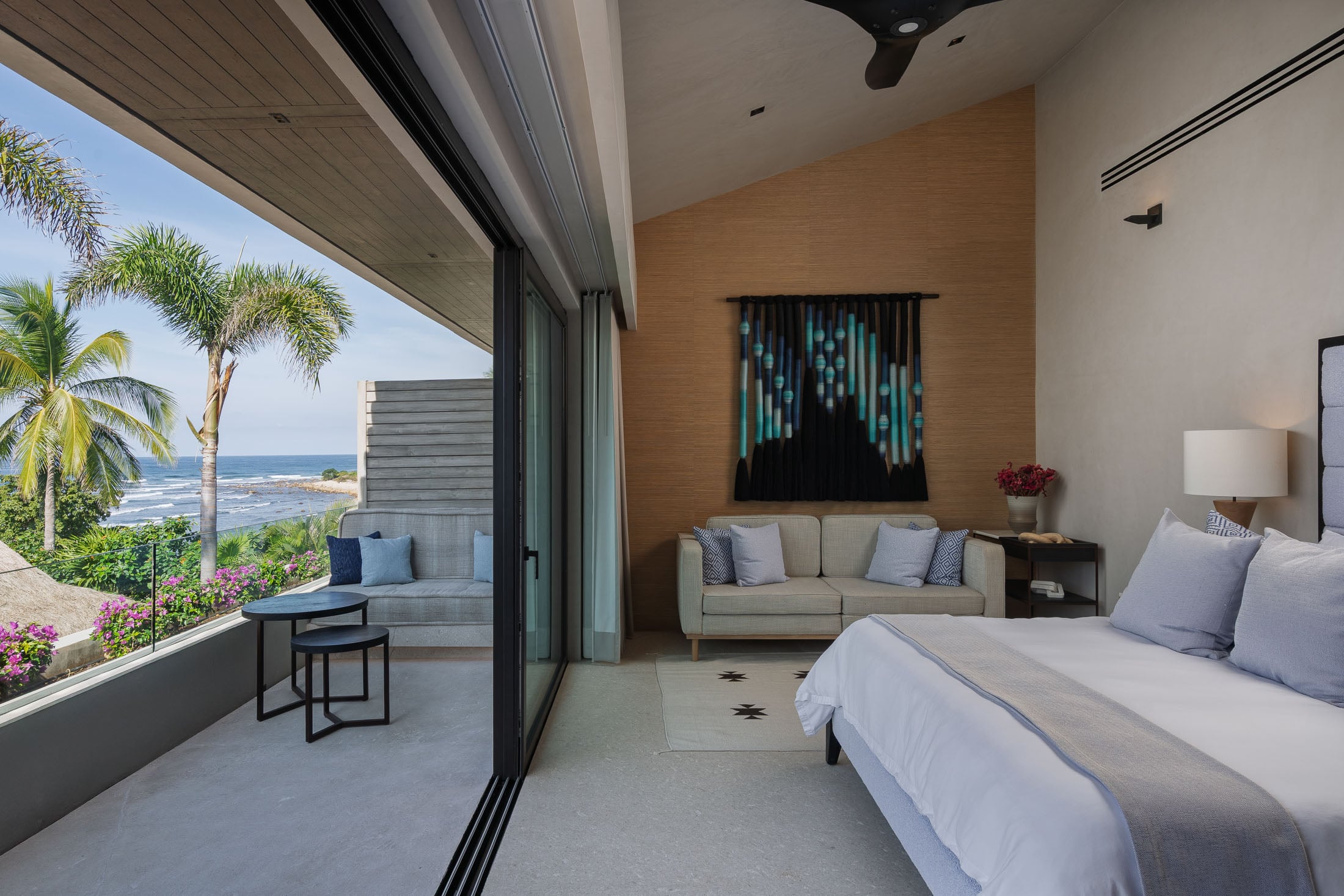 Estate Elementos bedroom with a teal wall hanging and a terrace bench facing the sea — Punta Mita Nayarit, Mexico