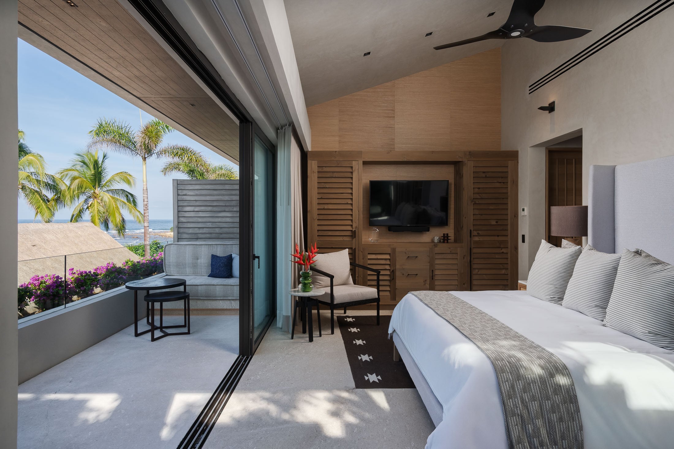 Estate Elementos bedroom with louvred wardrobe doors and red flowers by the terrace — Punta Mita Nayarit, Mexico