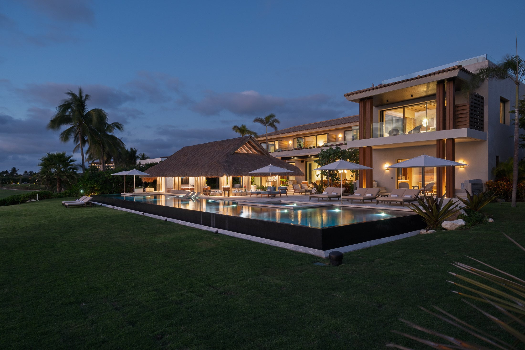 Estate Elementos lit house and palapa reflected in the pool at dusk — Punta Mita Nayarit, Mexico