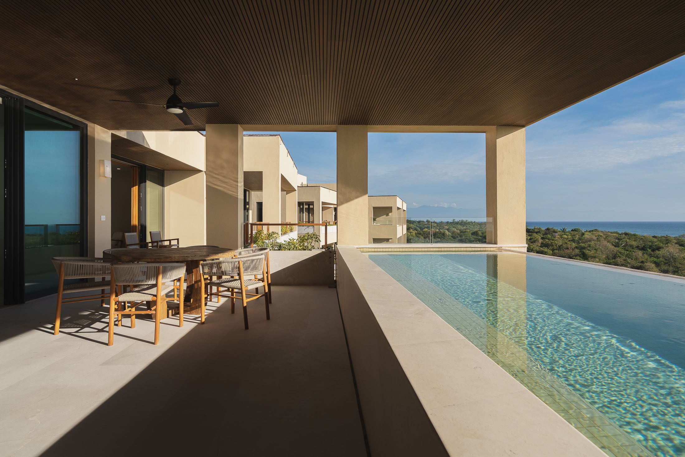 Penthouse ArenaMar the long lap pool beside the shaded dining table on the terrace — Punta Mita, Mexico