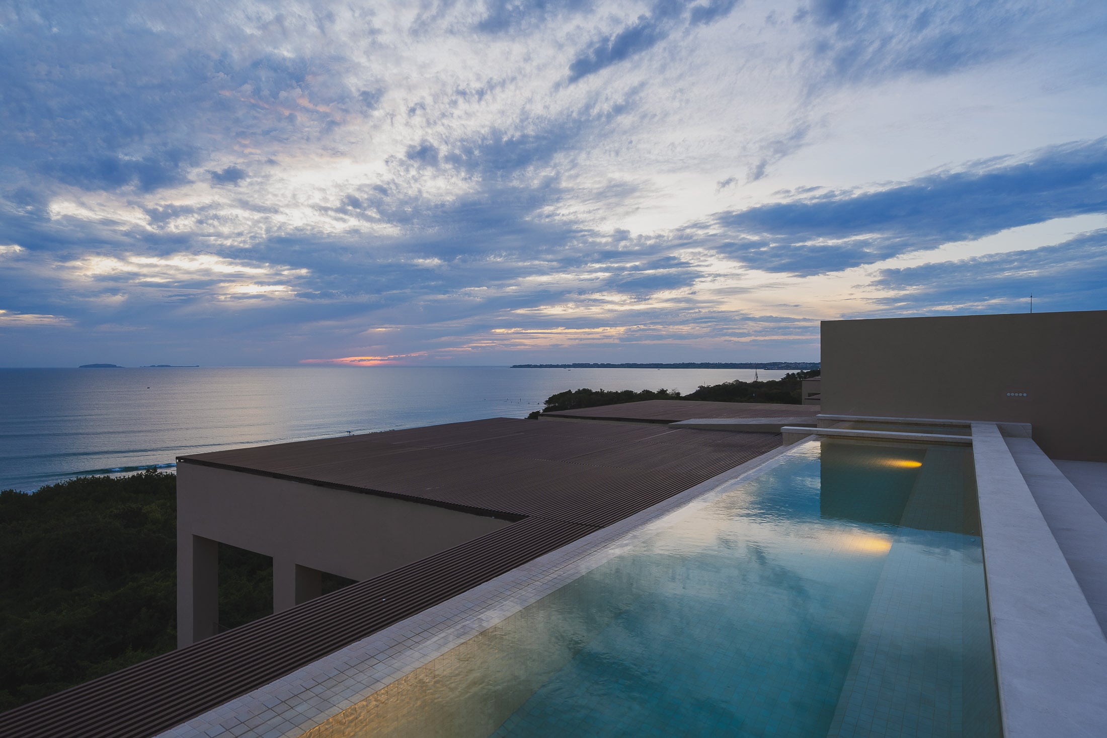 Penthouse ArenaMar cloud banks over the sea beyond the lit rooftop pool at dusk — Punta Mita, Mexico